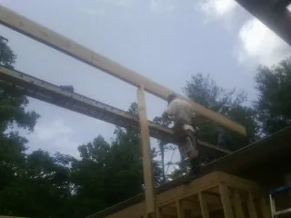 Carpenter setting a ridge beam over a new addition frame — Ice Dam Removal by Roofing Brothers in Burtonsville