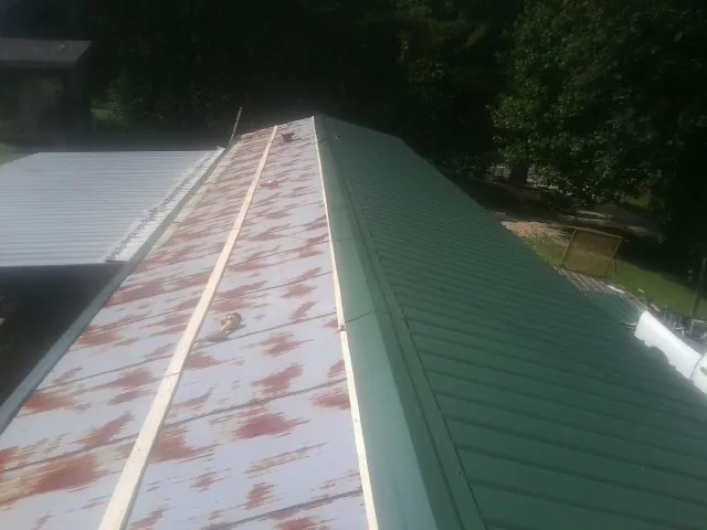 Old rusted panels beside newly installed green metal roofing — Wind Damage Roof Repair by Roofing Brothers in Burtonsville
