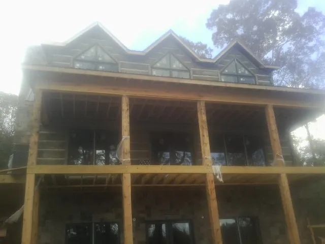 Dormers and porch framing on a large log home under construction — Roof Coating work by our crew in Burtonsville