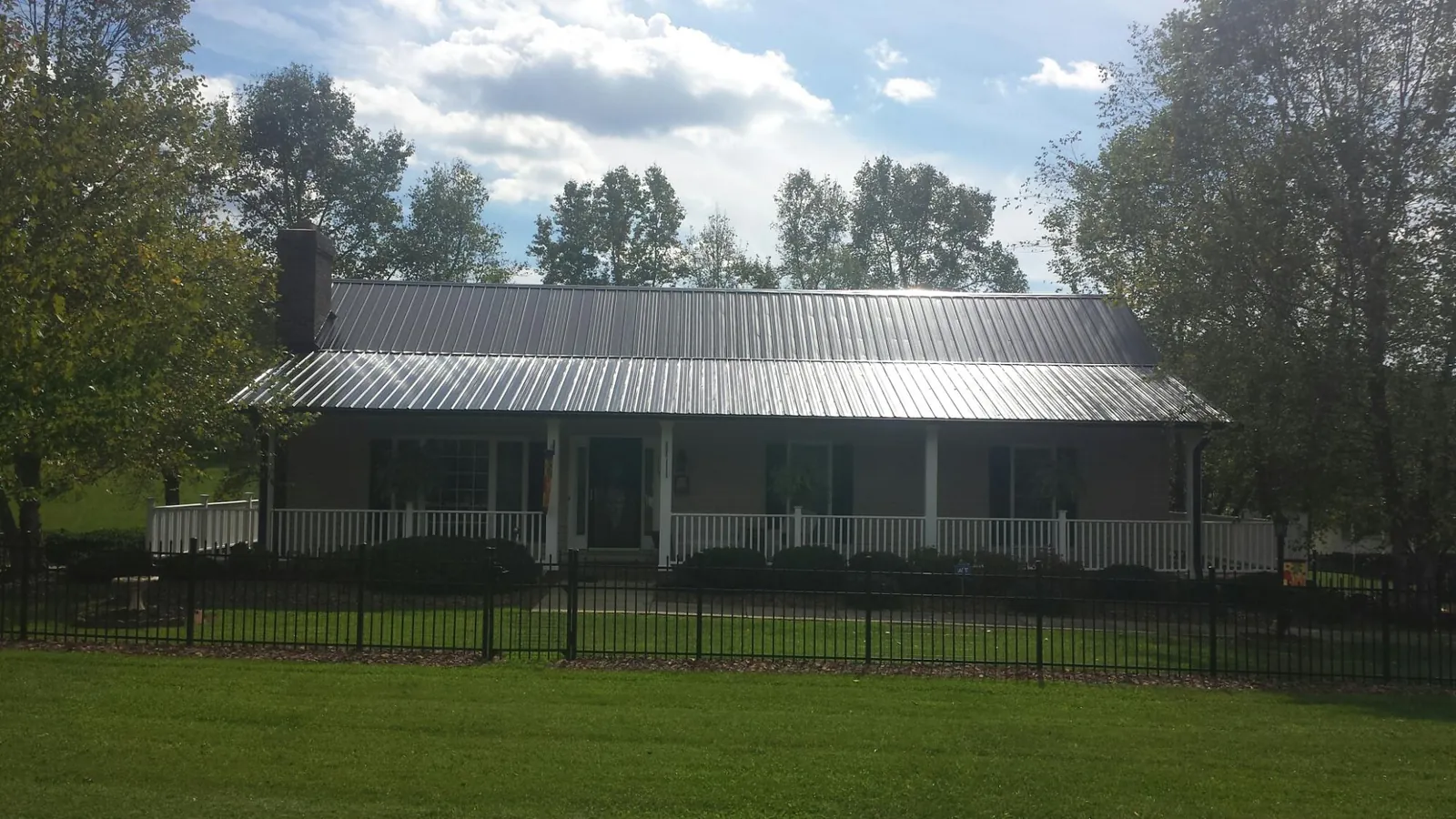 Gray metal roof on a brick ranch with a full width front porch — Gutter Guard Installation work by our crew in Burtonsville