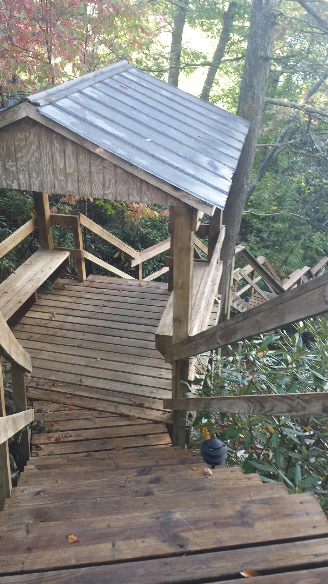 Metal roofed shelter over wooden steps on a wooded walkway — Skylight Repair & Installation work by our crew in Burtonsville