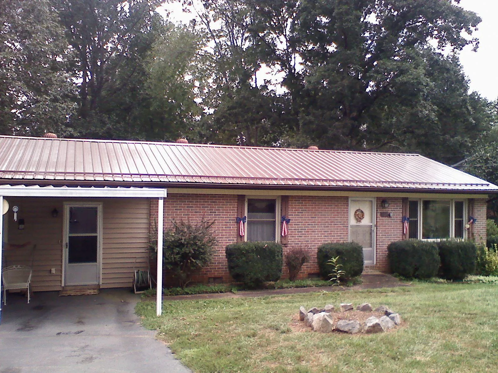 Bronze metal roof and carport on a brick ranch home — Roof Repair work by our crew in Burtonsville