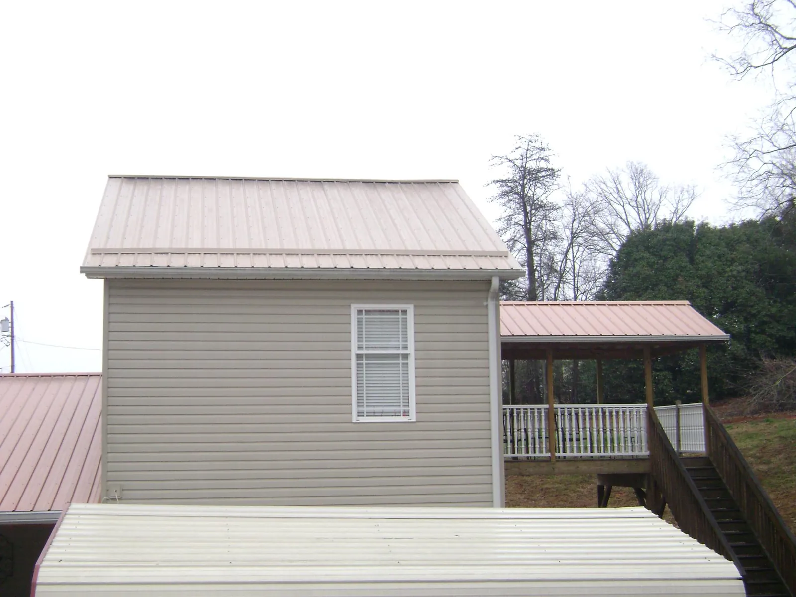 Tan metal roofs on a two story addition and attached porch, from a Roof Replacement job in Burtonsville