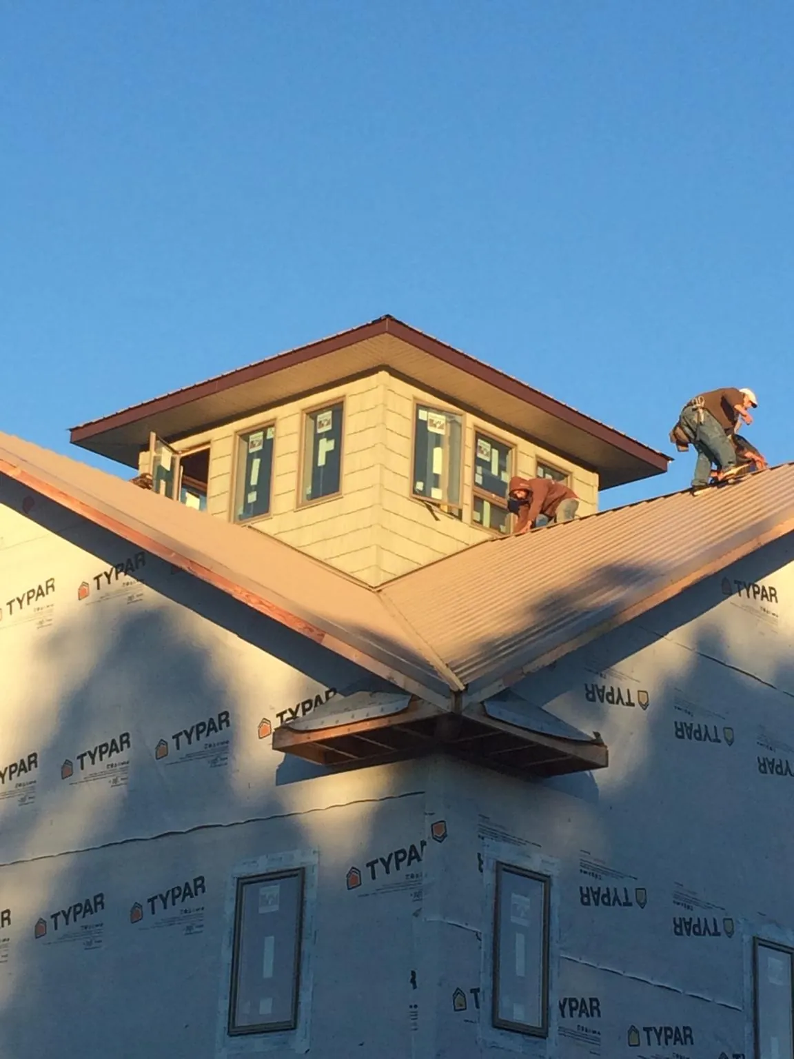 Roofers working around a rooftop cupola on a new metal roof at sunset — Roof Waterproofing in Burtonsville by Roofing Brothers